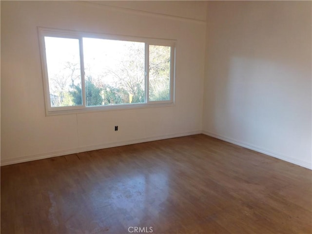 empty room with a wealth of natural light, baseboards, and wood finished floors