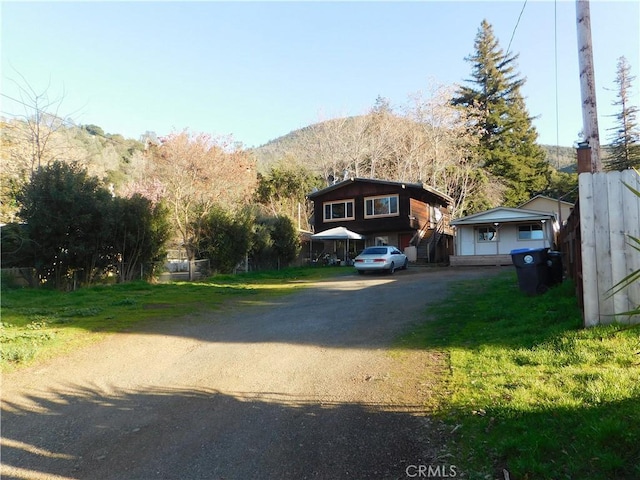 view of front of property featuring driveway, a mountain view, and a front yard