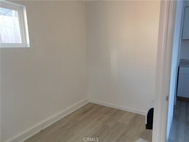 clothes washing area featuring light wood finished floors and baseboards