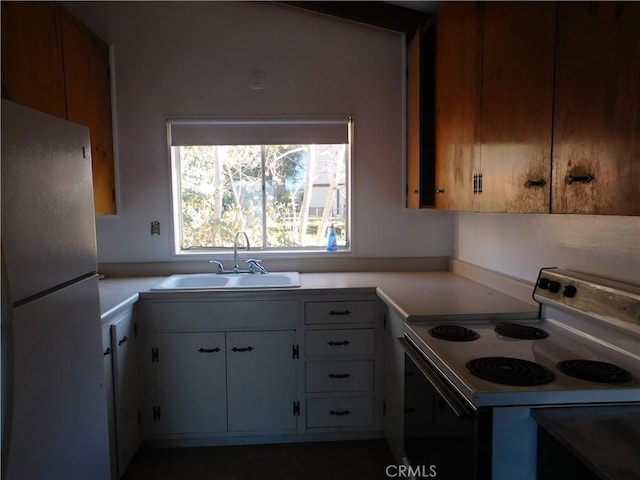 kitchen featuring range with electric stovetop, a sink, white cabinetry, light countertops, and freestanding refrigerator