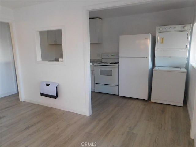 kitchen featuring light wood finished floors, light countertops, white appliances, and stacked washer / dryer