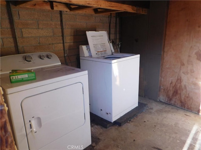 clothes washing area featuring washing machine and dryer, laundry area, and concrete block wall