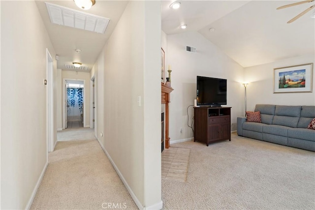 hallway with light colored carpet, visible vents, lofted ceiling, and baseboards