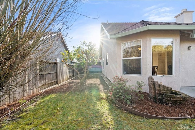 view of property exterior featuring a fenced backyard, roof with shingles, a chimney, and stucco siding