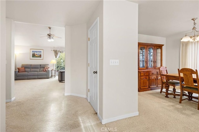 corridor featuring a chandelier, carpet, and baseboards