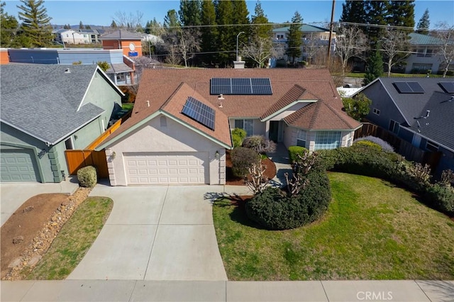 view of front of property with solar panels, fence, a garage, a residential view, and driveway