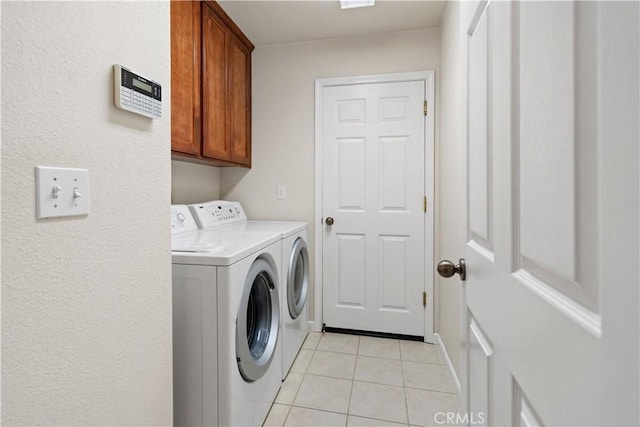 clothes washing area featuring light tile patterned floors, cabinet space, and washer and dryer