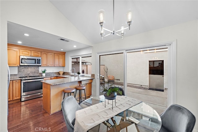 kitchen with stainless steel appliances, visible vents, hanging light fixtures, a sink, and a peninsula