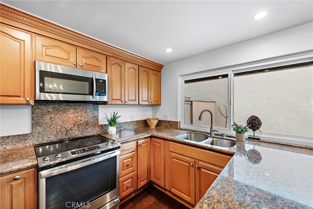 kitchen featuring stainless steel appliances, recessed lighting, stone counters, and a sink