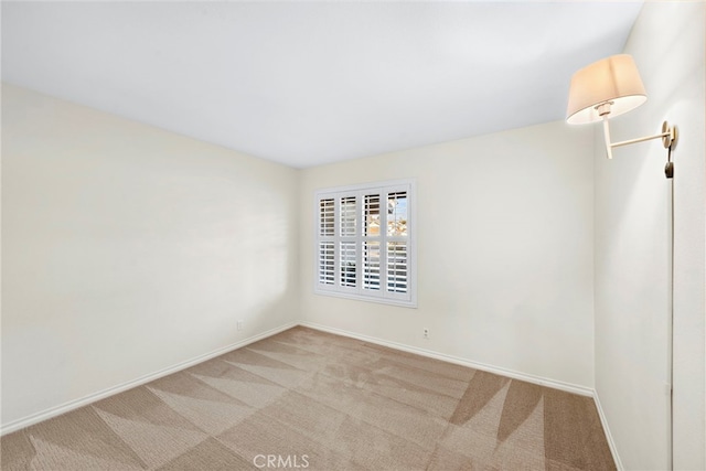 empty room featuring light colored carpet and baseboards