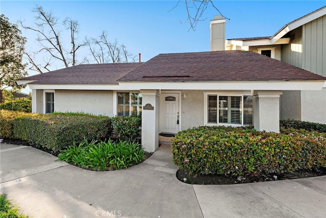 ranch-style house with roof with shingles and stucco siding