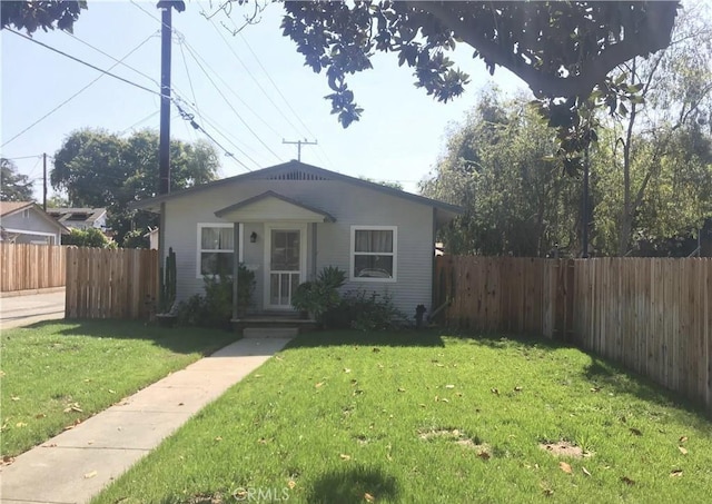 bungalow-style house with a front lawn and fence private yard