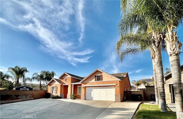 view of front of house with a garage, fence, concrete driveway, and brick siding