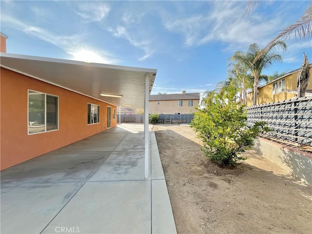 view of property exterior with a patio, fence, and stucco siding