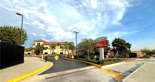 view of street with curbs, a gate, a gated entry, and street lights