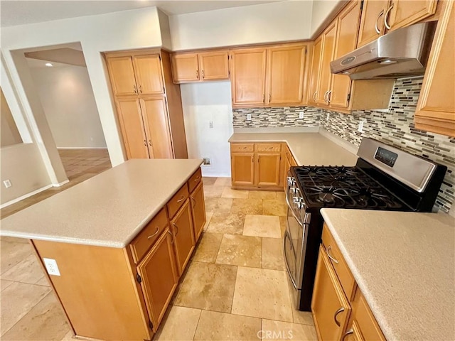 kitchen with under cabinet range hood, tasteful backsplash, light countertops, and gas range