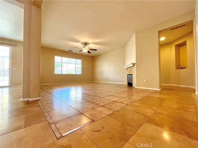 unfurnished living room with visible vents, baseboards, a glass covered fireplace, ceiling fan, and light tile patterned flooring