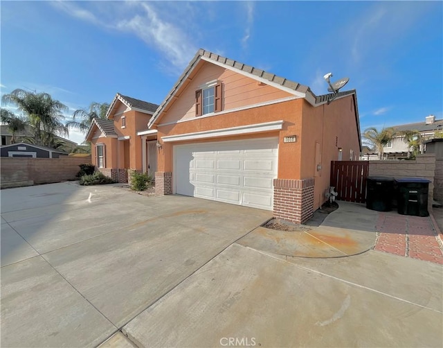 view of home's exterior with a garage, driveway, fence, and stucco siding