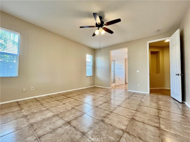 empty room featuring ceiling fan and baseboards