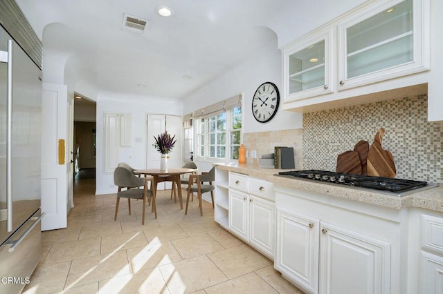 kitchen featuring visible vents, decorative backsplash, glass insert cabinets, stainless steel appliances, and white cabinetry