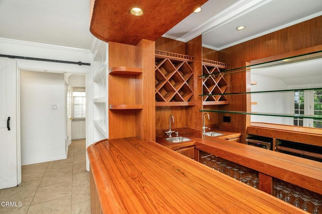 wine room featuring indoor wet bar, a sink, light tile patterned flooring, and crown molding