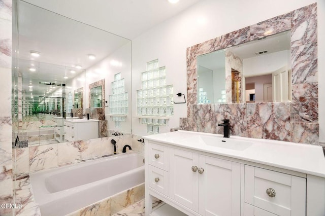 bathroom with marble finish floor, tile walls, visible vents, a sink, and a bath