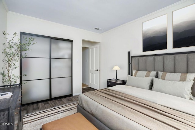 bedroom featuring crown molding, visible vents, and dark wood finished floors