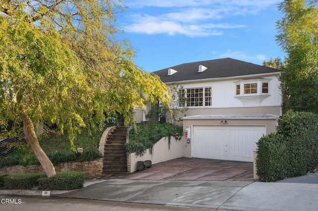 view of front of home with a garage, stucco siding, driveway, and stairs