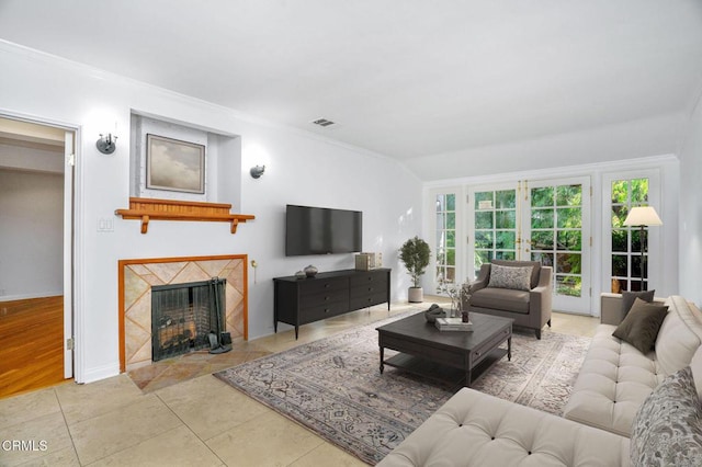 living room with french doors, crown molding, light tile patterned floors, visible vents, and a premium fireplace