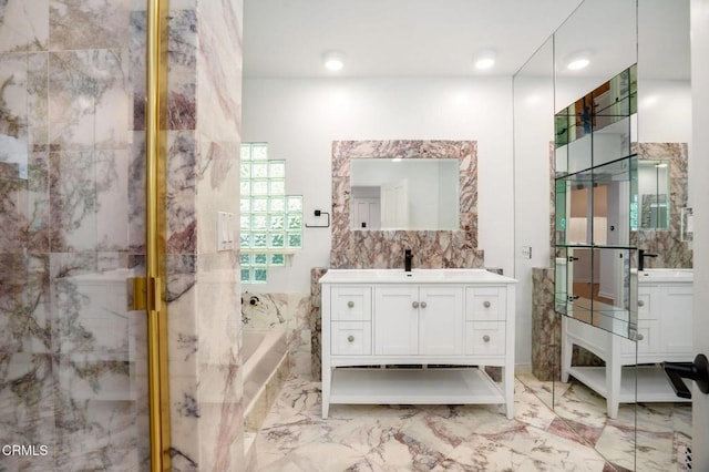 bathroom featuring marble finish floor, a garden tub, vanity, a shower stall, and tile walls