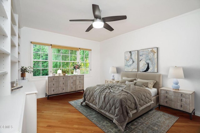 bedroom with baseboards, ceiling fan, ornamental molding, and wood finished floors