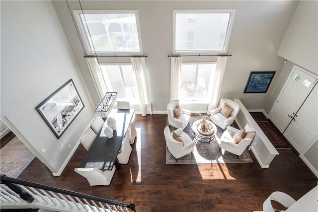 living area featuring a high ceiling, baseboards, and dark wood finished floors