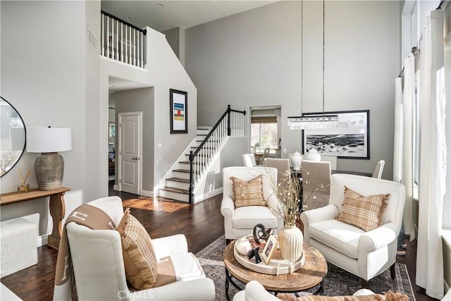 living area with baseboards, stairs, a high ceiling, and dark wood-style flooring