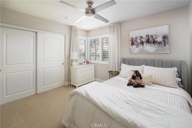 bedroom featuring light carpet, a ceiling fan, and a closet