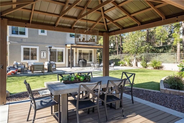 wooden deck featuring a gazebo, outdoor dining space, a lawn, and fence