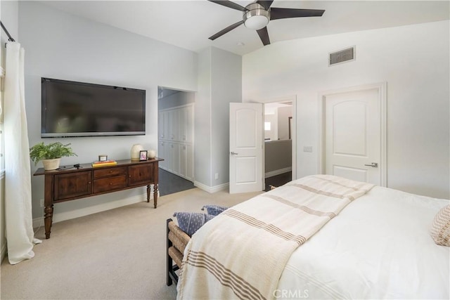 bedroom featuring a closet, light colored carpet, visible vents, vaulted ceiling, and baseboards