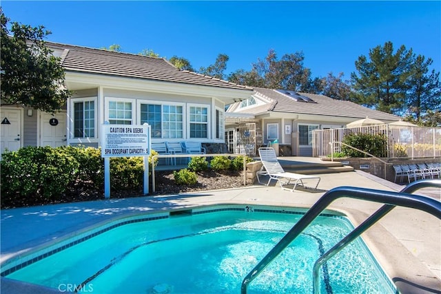 back of property featuring a tiled roof, a patio area, fence, and a pool