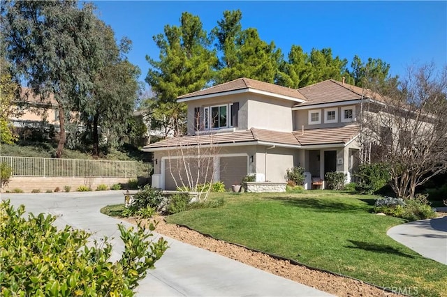 view of front of property featuring fence, concrete driveway, a tiled roof, stucco siding, and a front yard