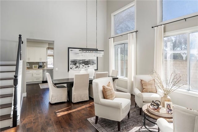 dining space with dark wood-style floors, a high ceiling, stairway, and baseboards