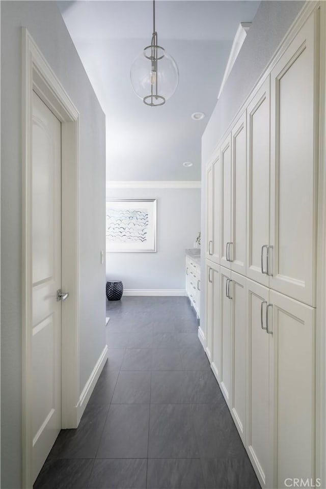 corridor with dark tile patterned flooring and baseboards