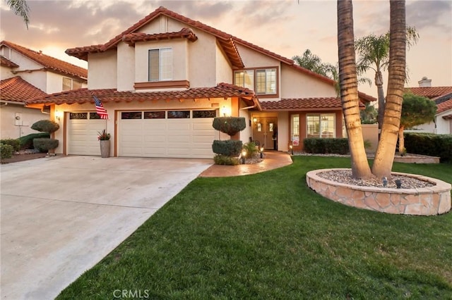 mediterranean / spanish home with driveway, a tile roof, an attached garage, a front lawn, and stucco siding