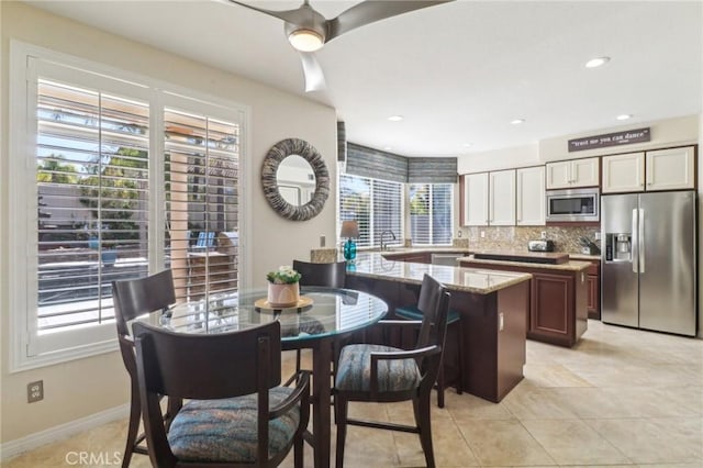 kitchen featuring light stone counters, recessed lighting, a peninsula, appliances with stainless steel finishes, and tasteful backsplash