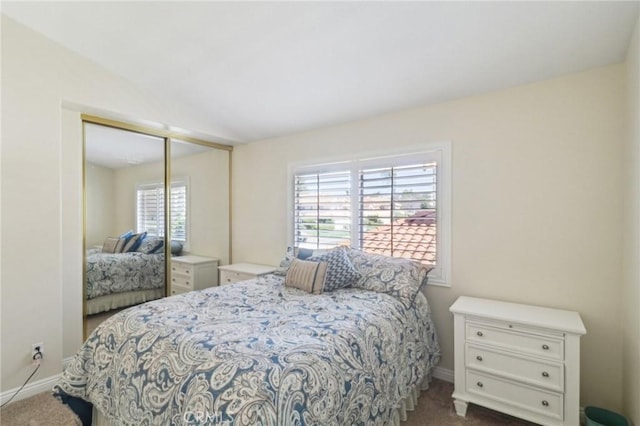 bedroom with baseboards, dark carpet, vaulted ceiling, and a closet