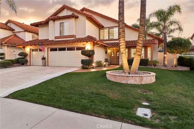 mediterranean / spanish-style home featuring an attached garage, a tile roof, a yard, driveway, and stucco siding