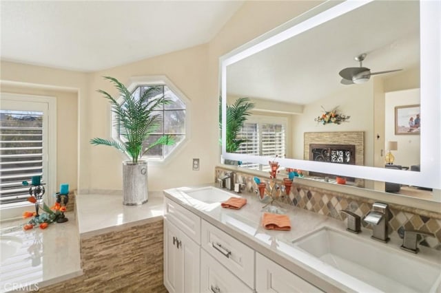 bathroom with double vanity, a fireplace, and a sink