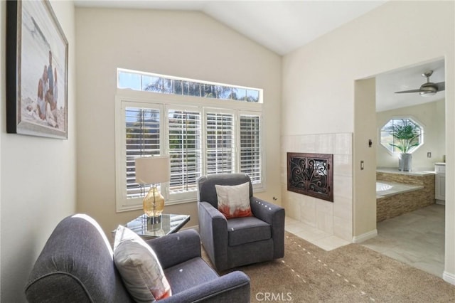 living area featuring light tile patterned floors, light colored carpet, ceiling fan, a fireplace, and high vaulted ceiling