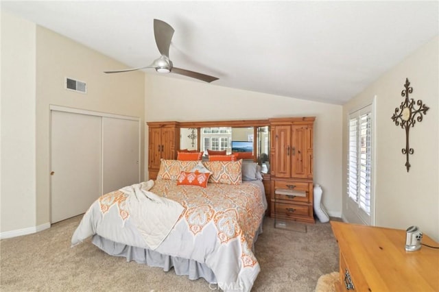 bedroom featuring a closet, light colored carpet, vaulted ceiling, and visible vents