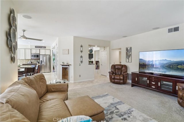 living room with wine cooler, light colored carpet, visible vents, a ceiling fan, and baseboards