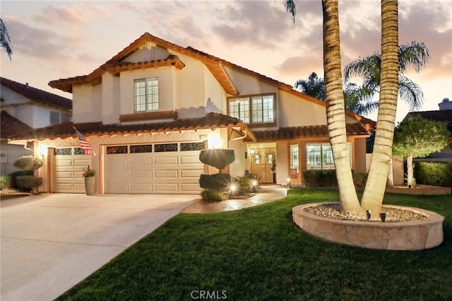 mediterranean / spanish-style house with a front lawn, concrete driveway, an attached garage, and stucco siding