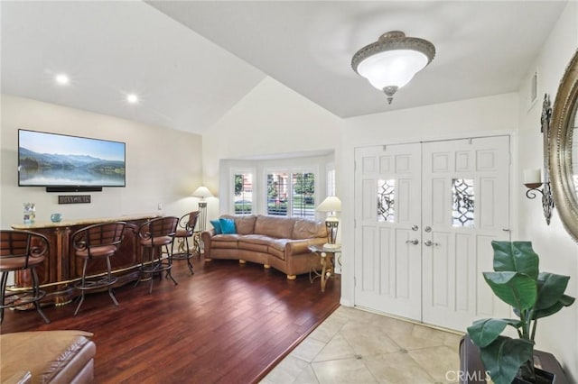 entryway with visible vents, lofted ceiling, light wood-style flooring, a bar, and recessed lighting